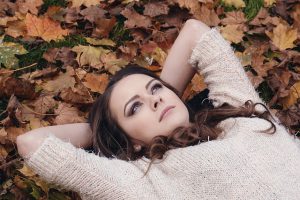 落ち葉の上で横になる女性